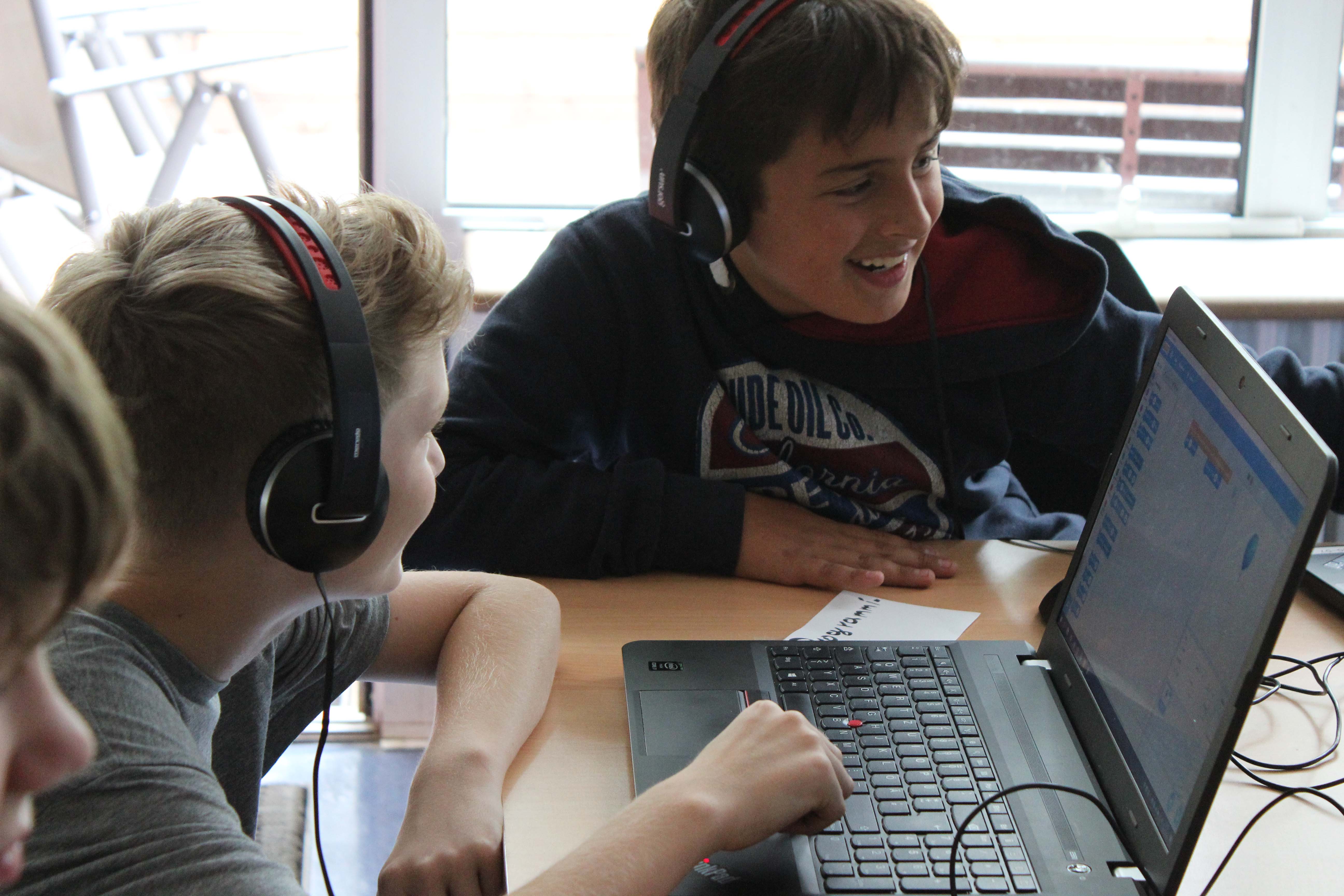 Jungen sitzen mit Kopfhörern vor einem Laptop