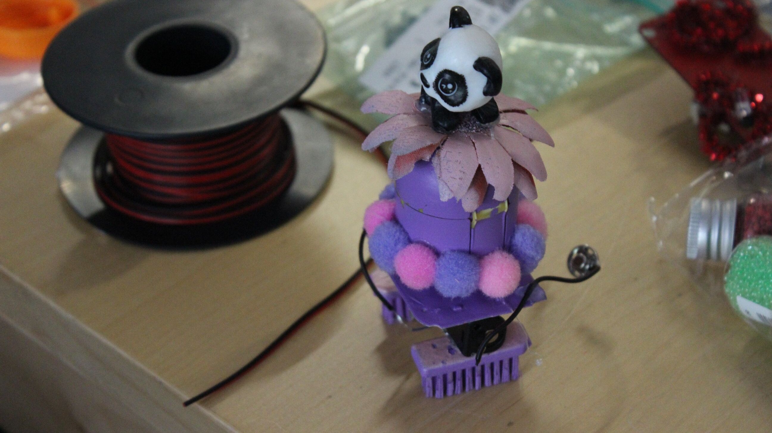 Bürstenroboter in lila Farben mit einer Pandabären-Figur auf der Spitze