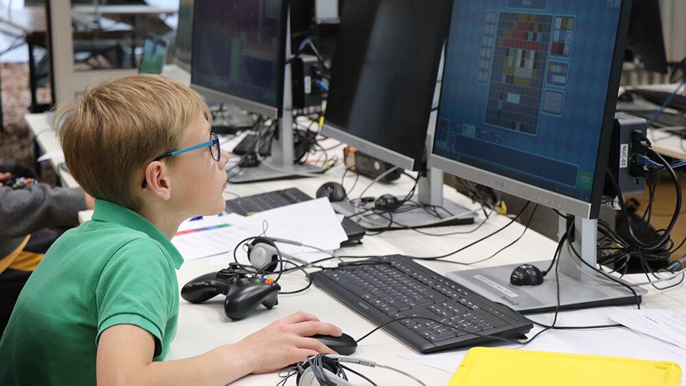 Junge sitzt am Computer und erstellt ein Spiel am Computer
