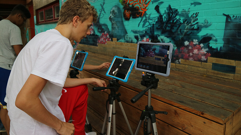 Mehrere Jungen filmen mit iPads eine bunte Wand