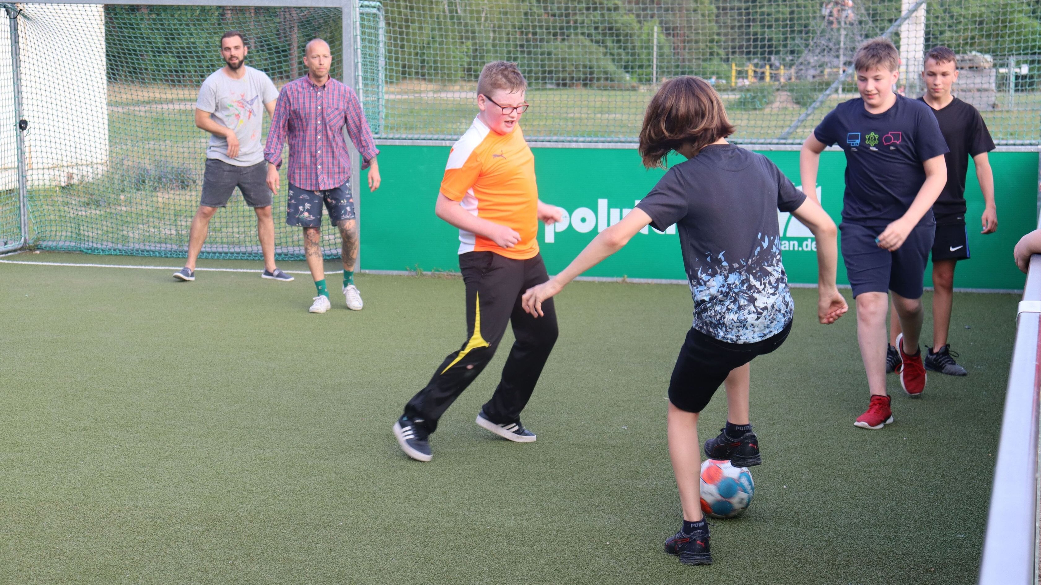 Jugendliche und Erwachsene spielen miteinander Fußball