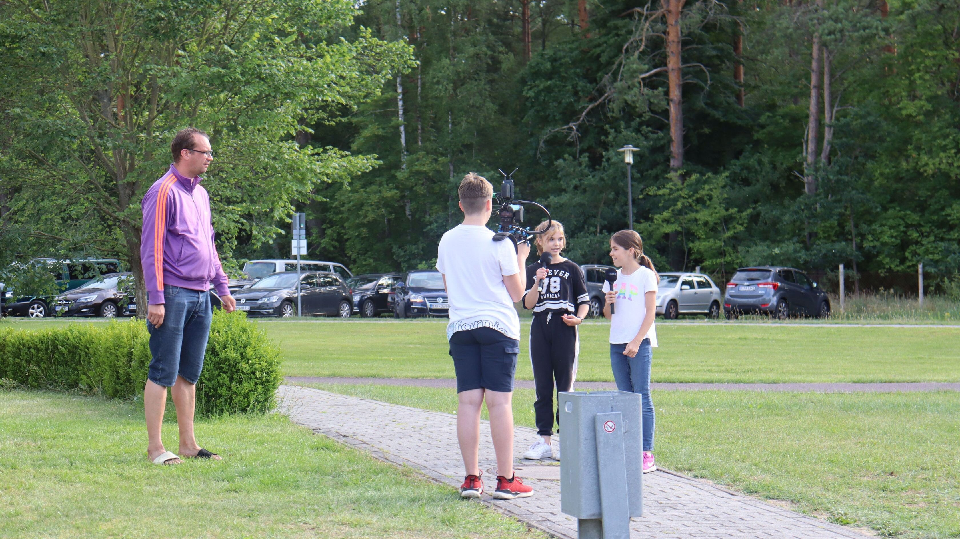 Jugendlicher filmt zwei Mädchen, die einander interviewen