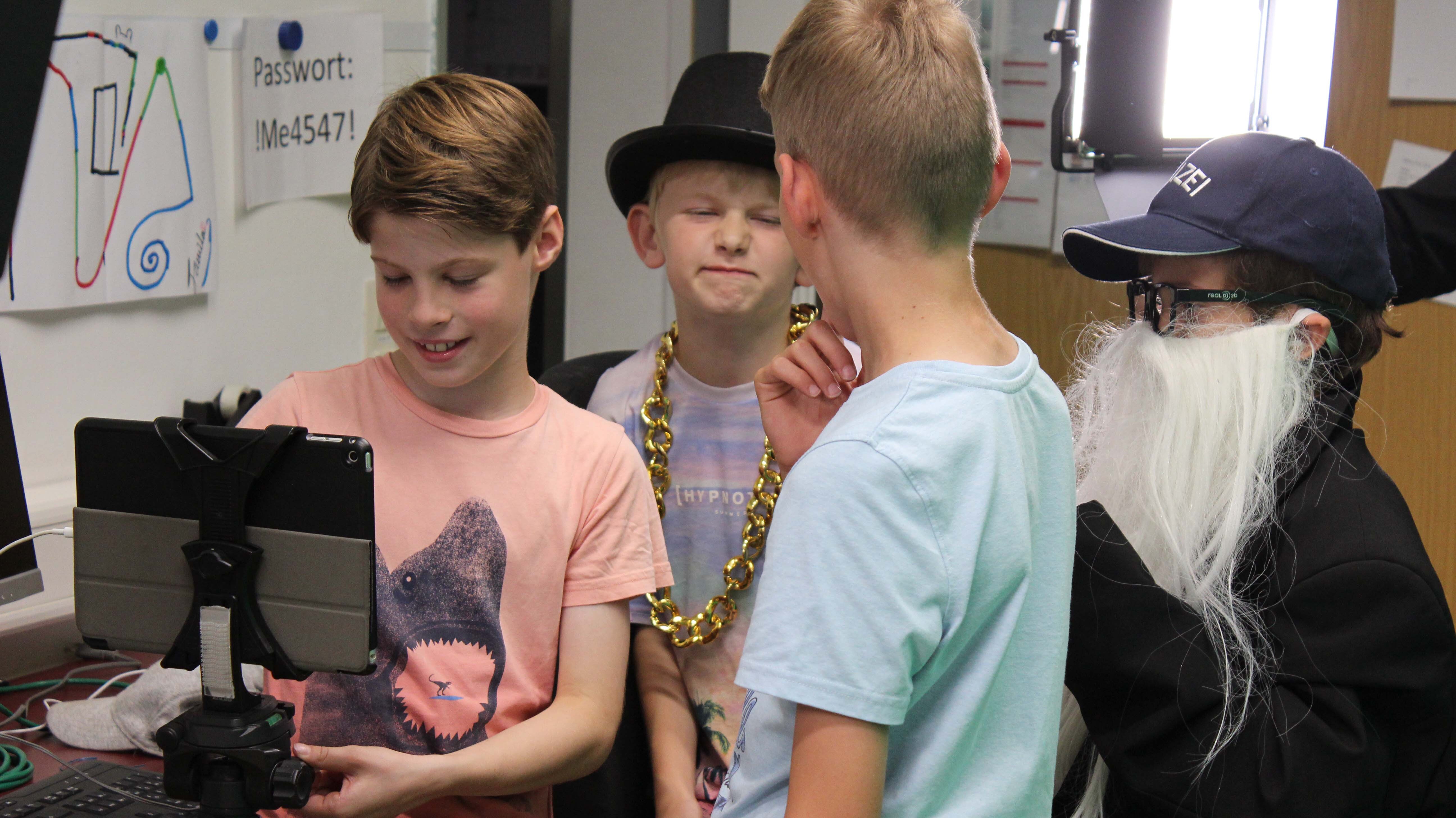 Jungen, manche verkleidet, bereiten Aufnahmen am Tablet vor
