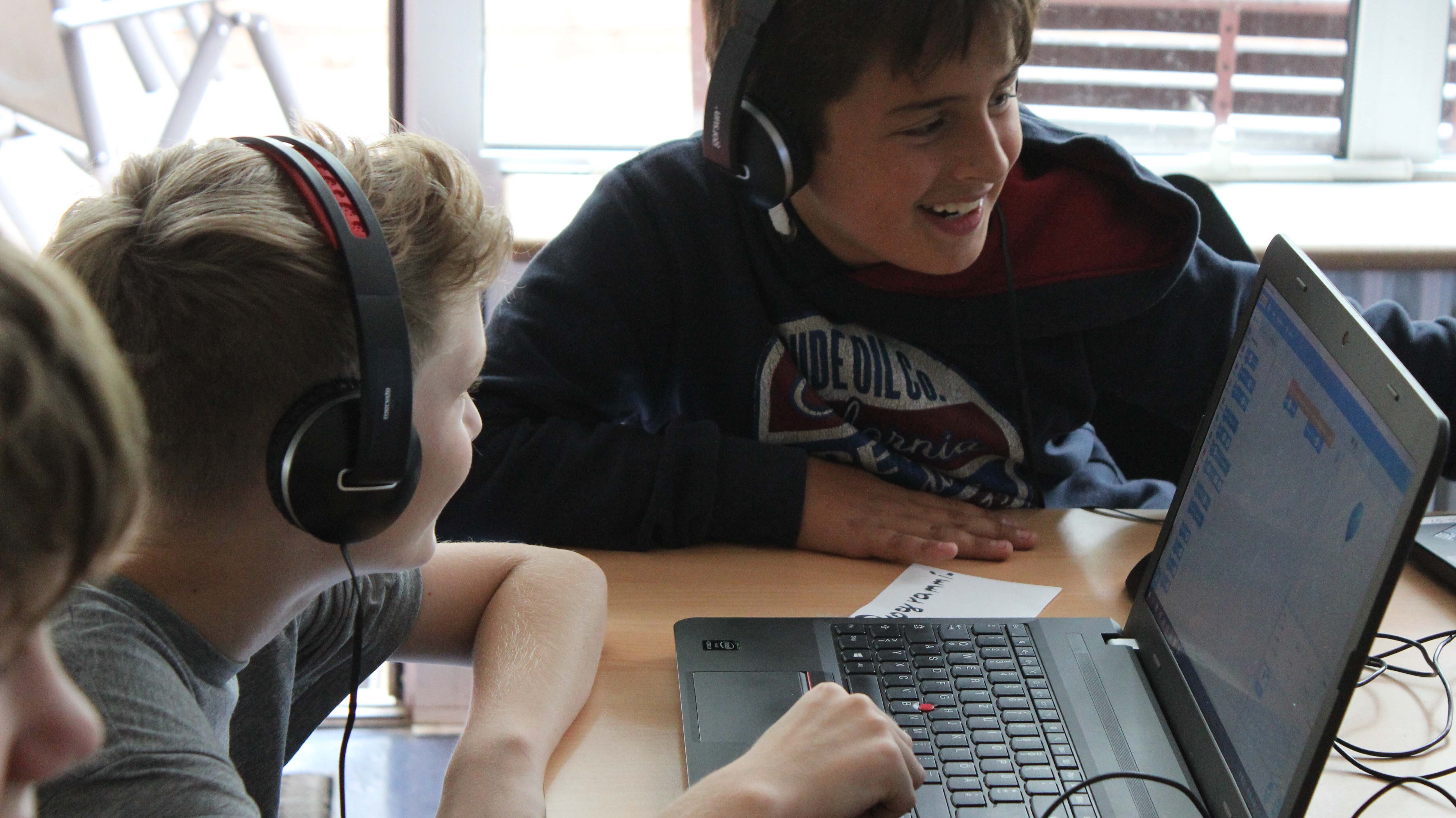 Jungen sitzen mit Kopfhörern vor einem Laptop