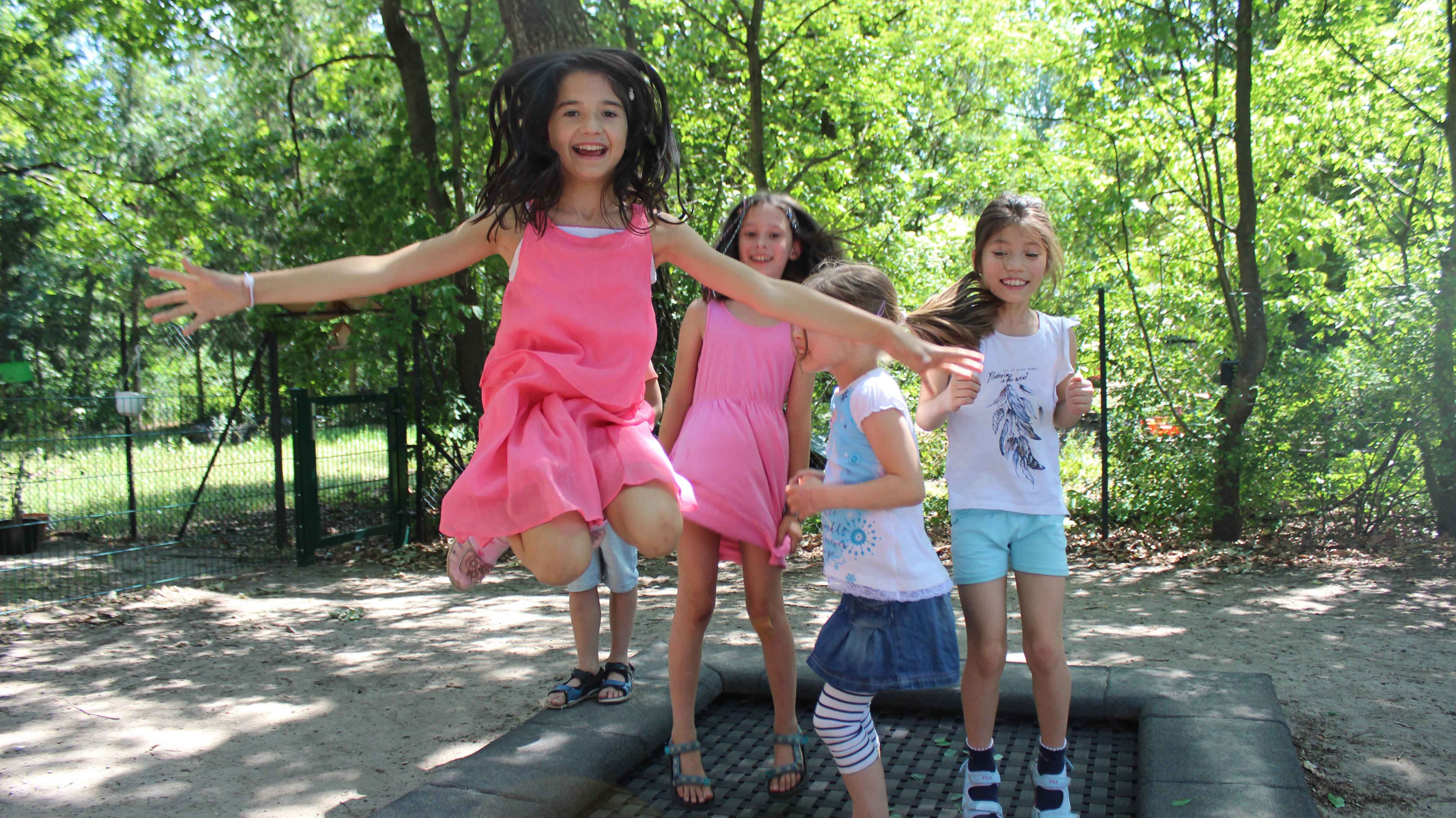 vier Mädchen hüpfen auf einem Bodentrampolin