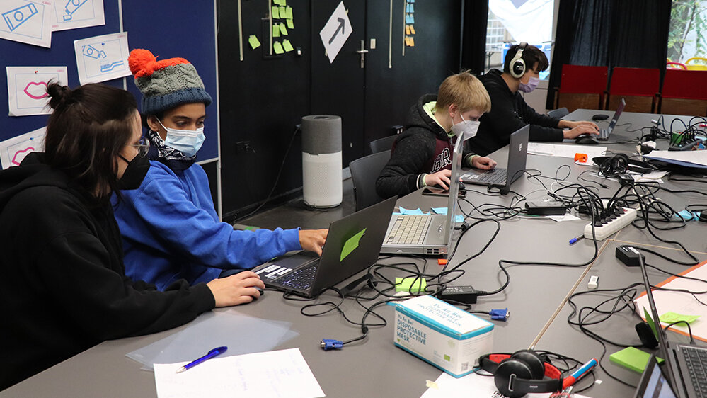 Gruppe von Kindern sitzt an einem Tisch und arbeitet am Computer