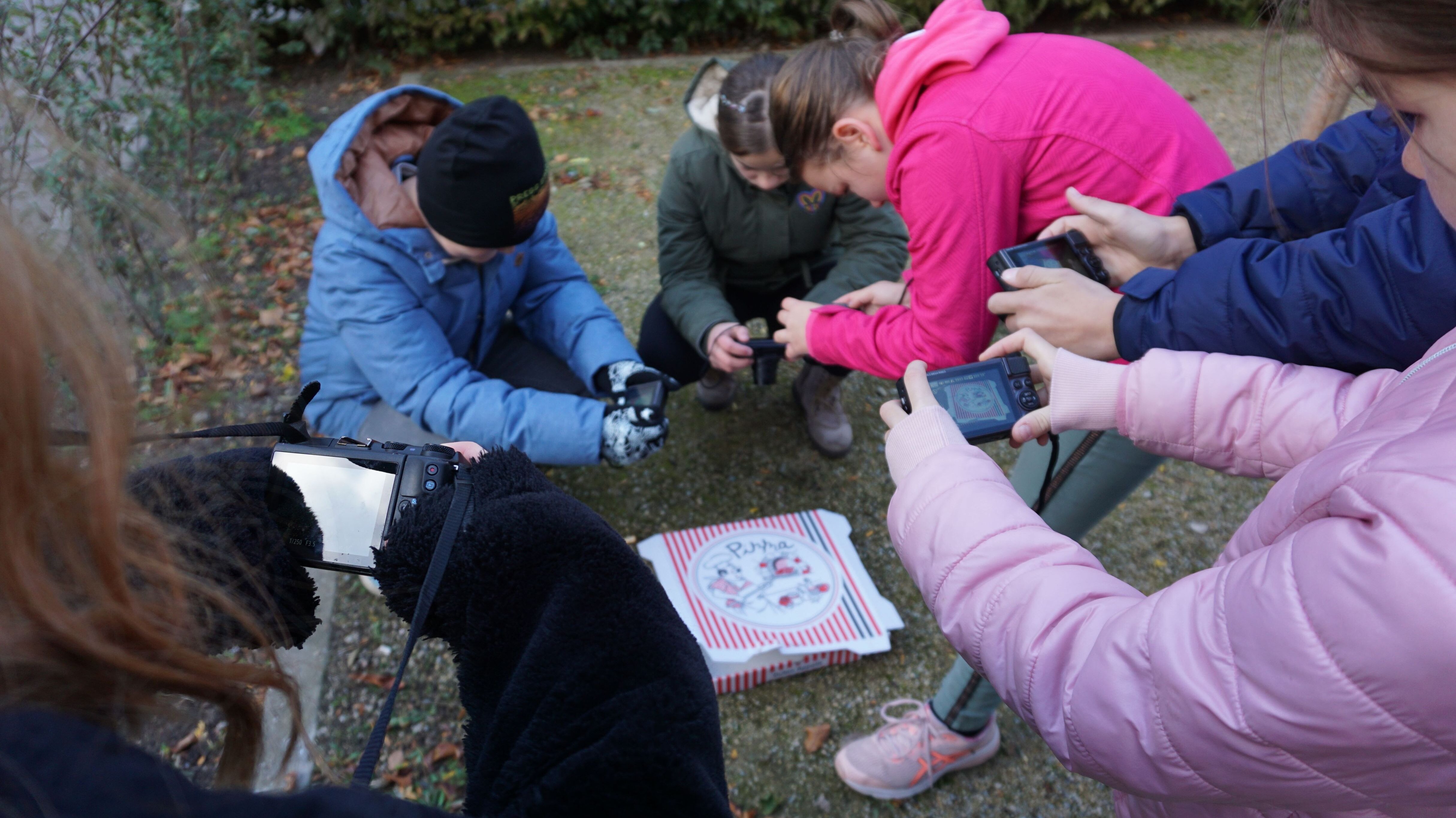 Gruppe von Kindern fotografiert eine Pizzaschachtel ab Boden
