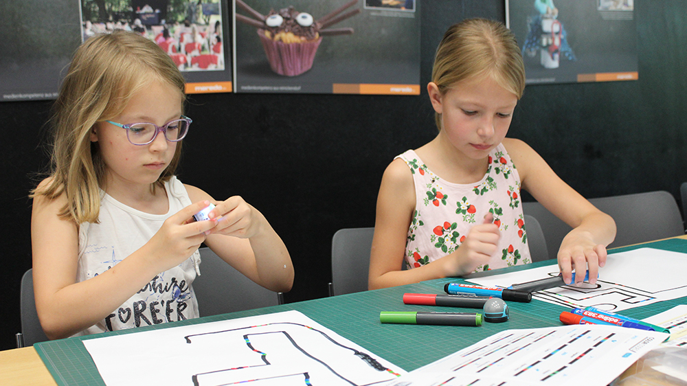 Zwei Kinder zeichnen Linien für die Ozobots