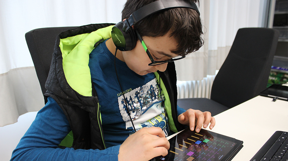 Ein Junge mit Kopfhörern tippt auf einem Tablet