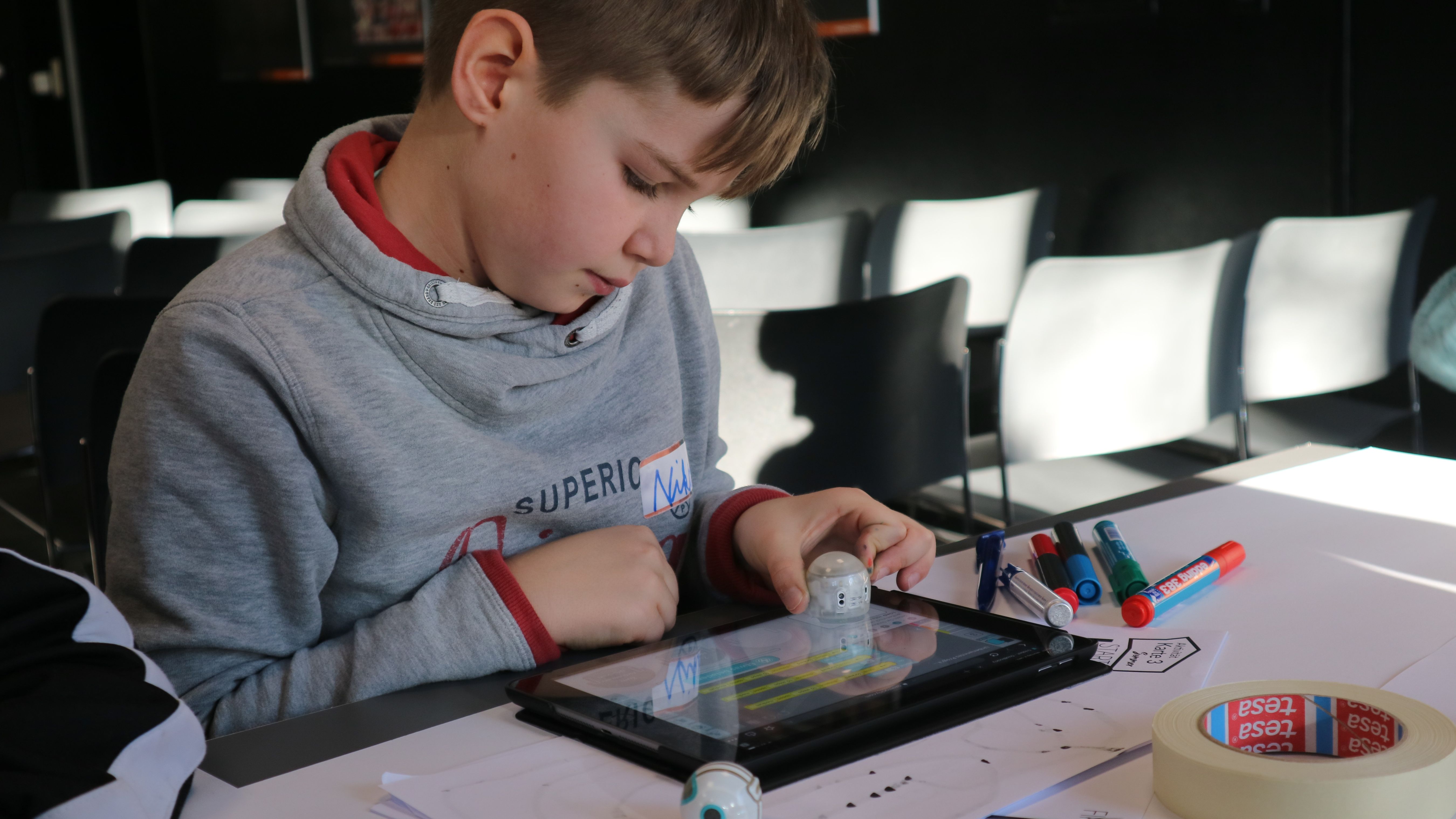 Junge programmiert kleinen Roboter mit dem Tablet