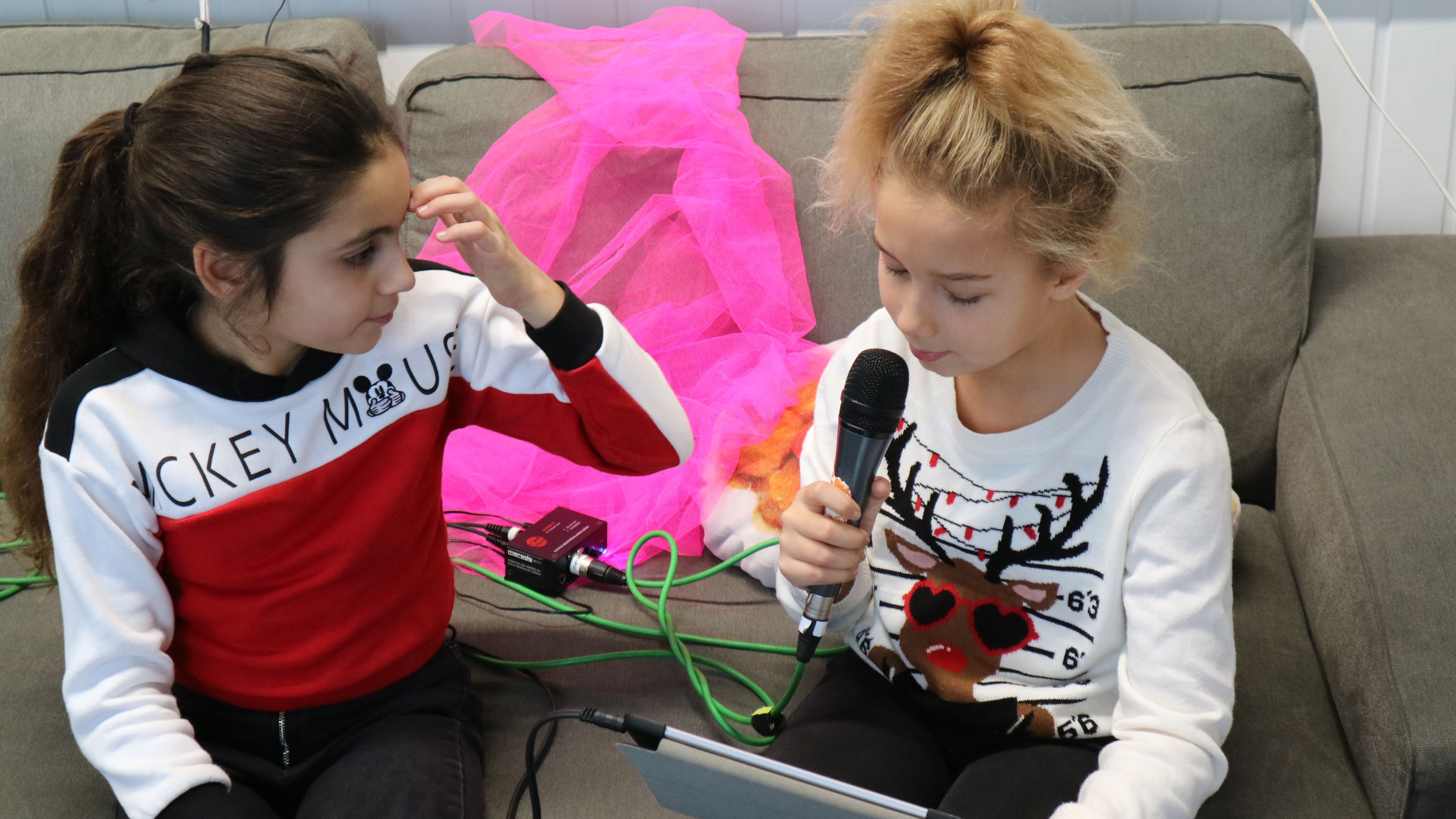 Zwei Mädchen nehmen ihre Stimmen mit dem Mikrofon auf.