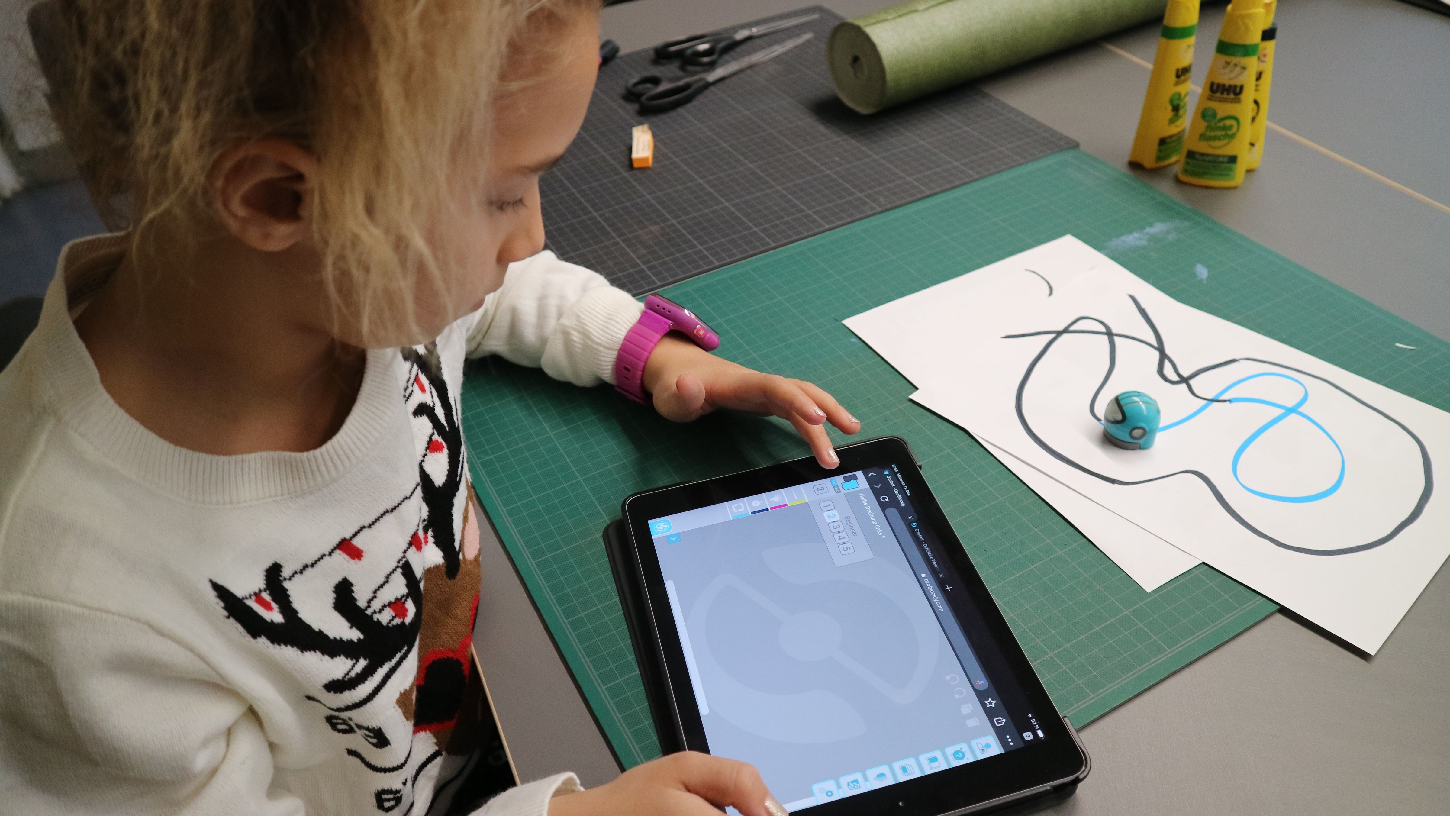 Mädchen programmiert Roboter mit Tablet