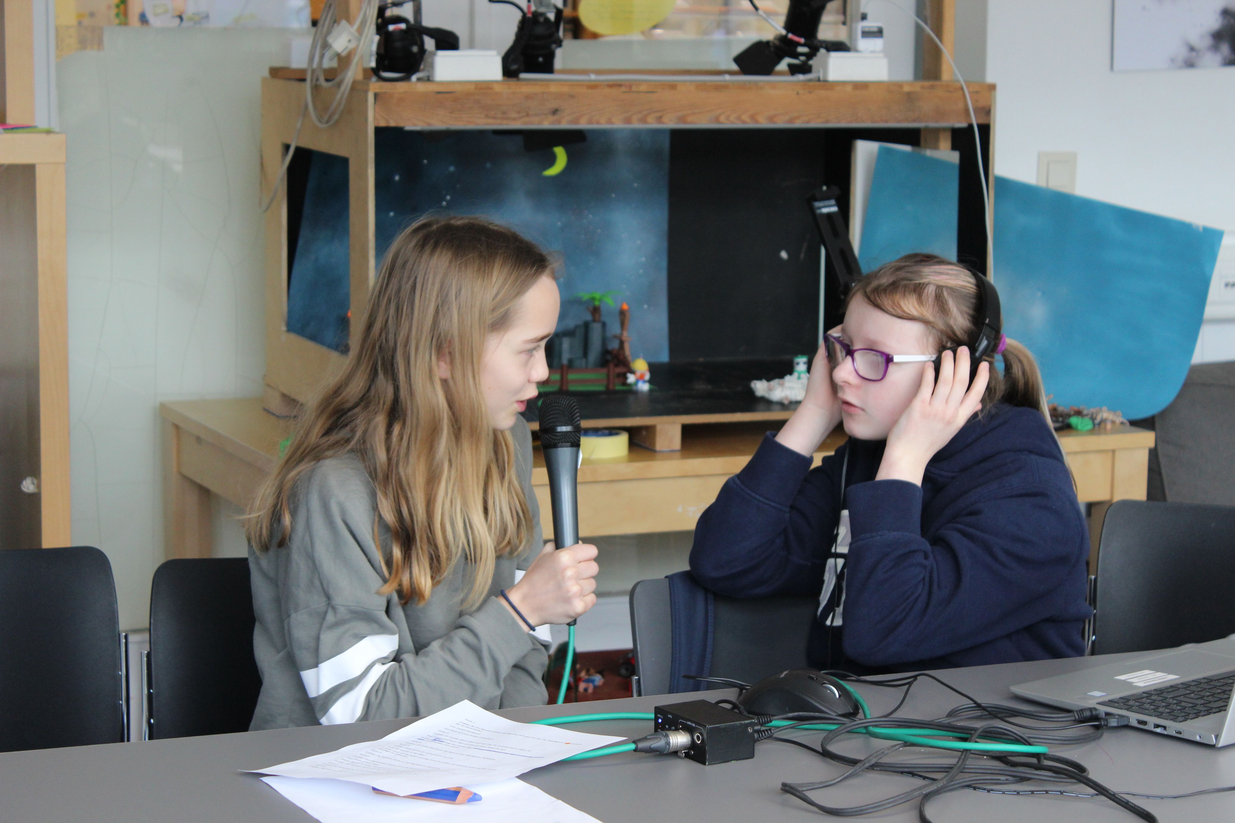 Zwei Schülerinnen hören sich mit Kopfhörern die Tonaufnahmen an